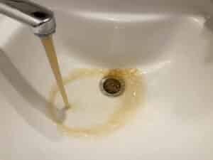 Dirty rusty brown polluted water flowing, Water Heater Maintenance.
